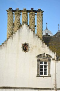 Francis waving from an attic window. Chimneys above. Winton House.