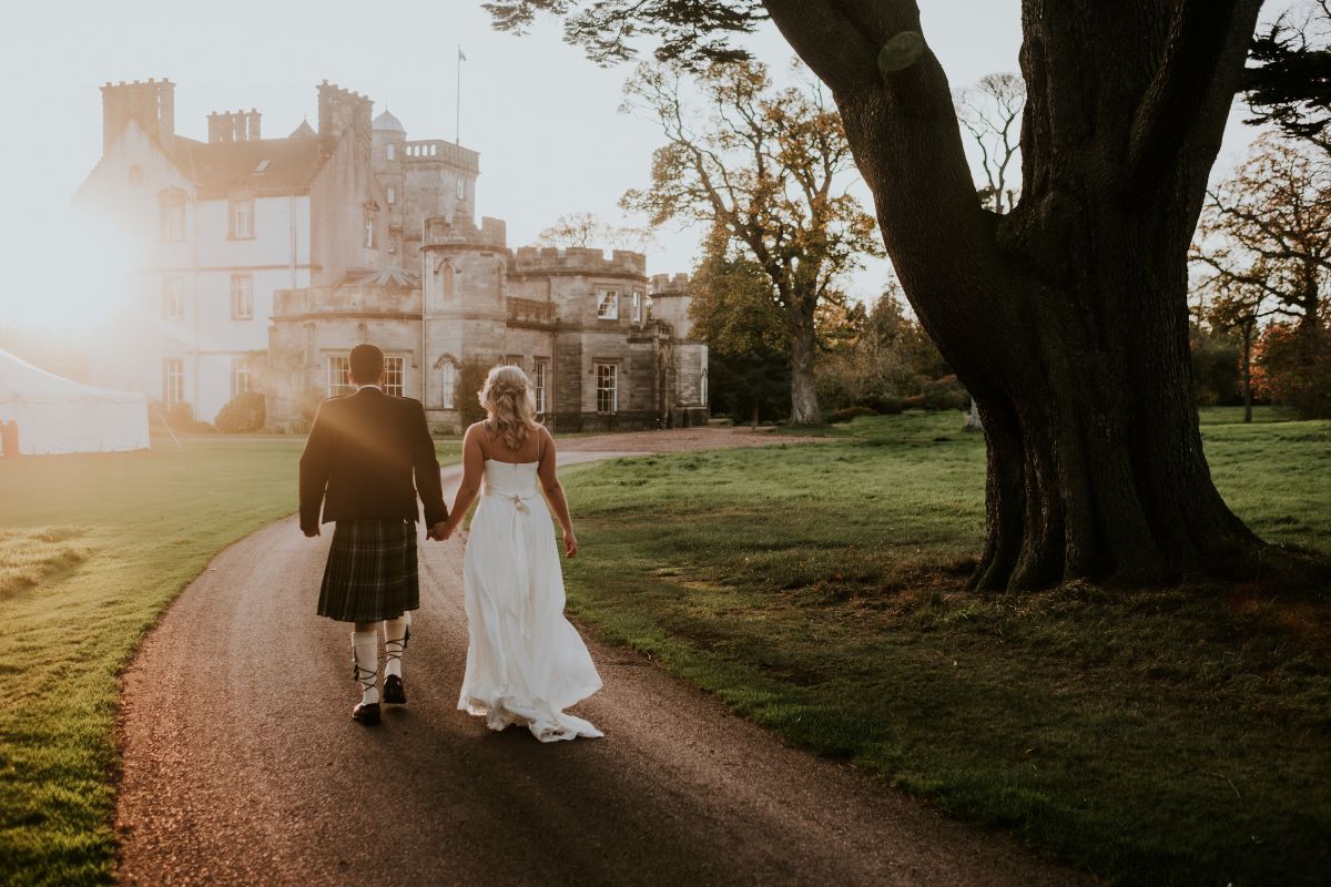 Bride and Groom in Golden Hour walking towards Castle